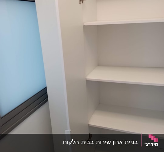 ארון לבן עם מדפים ודלת פתוחה